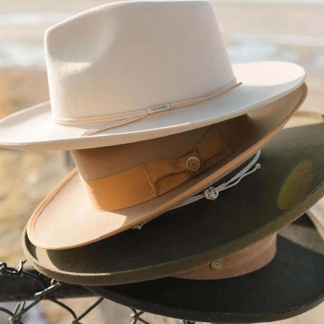 Four Two Roads men's hats for smaller heads stacked atop one another in white, brown, green, and black