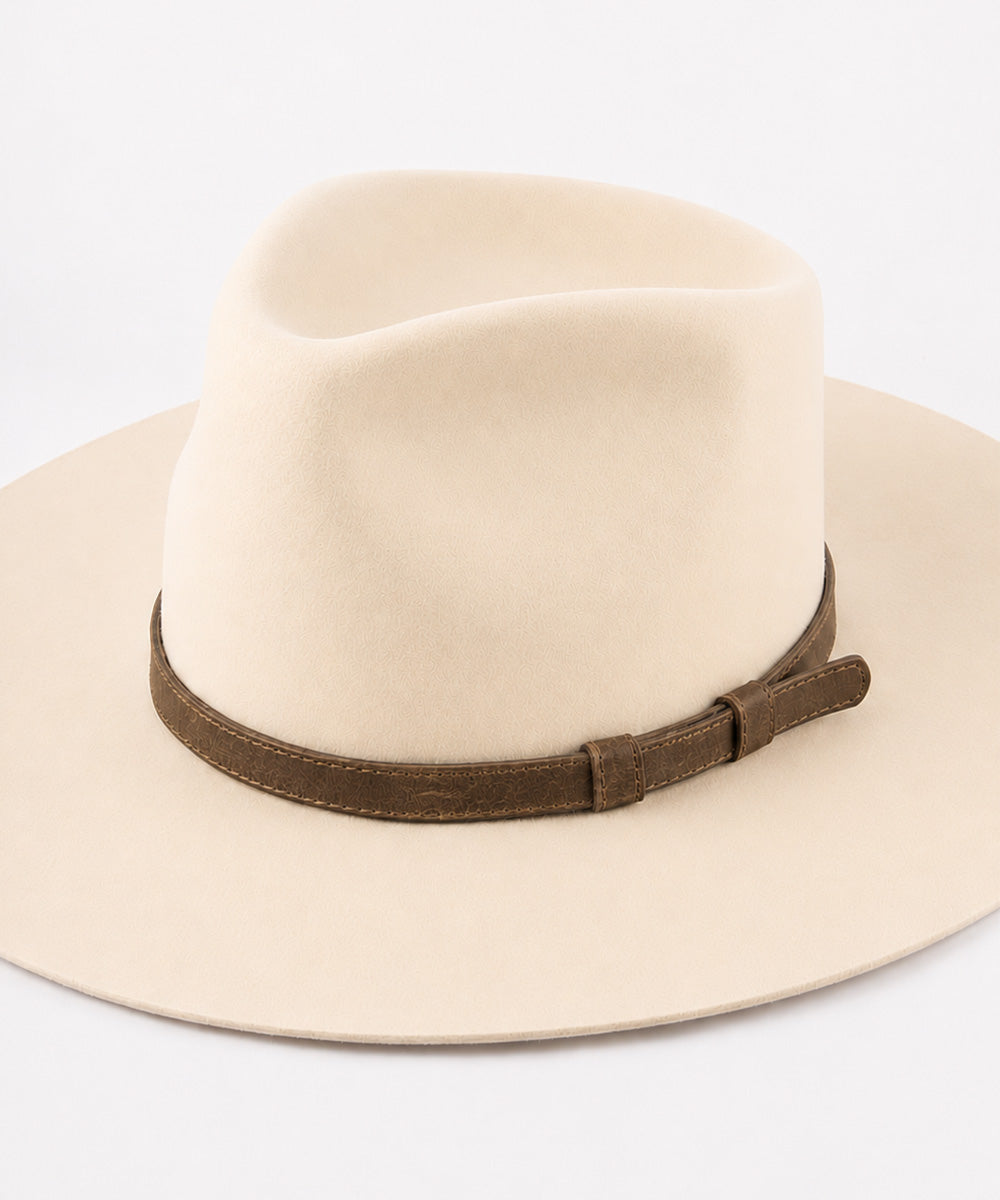 A cream-colored felt fedora hat with a brown leather band, shown from a side angle on a clean white background #color_brown