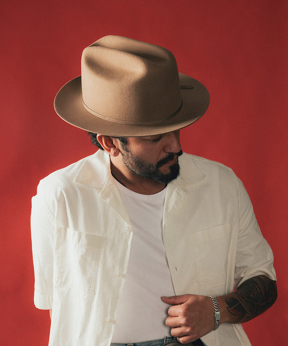 Man wearing a brown hat and white shirt against a red background #color_brown