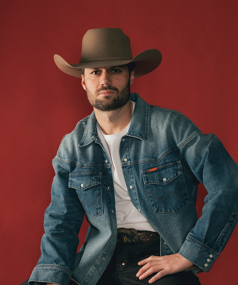 Man wearing a cowboy hat and denim jacket against a red background #color_brown