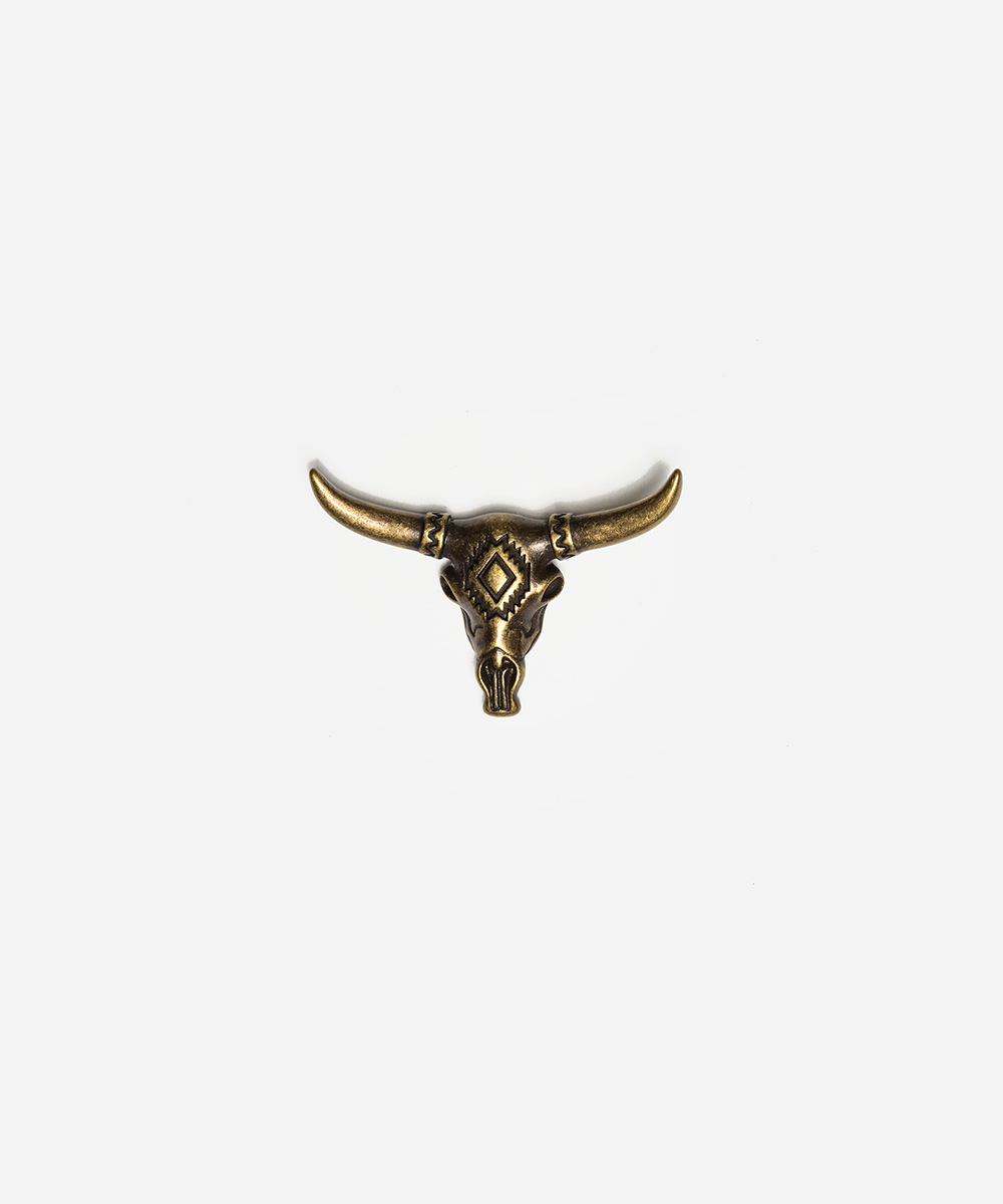 An antique bronze bull skull brooch with curved horns and detailed geometric engravings, centered on a light gray background #color_anti gold