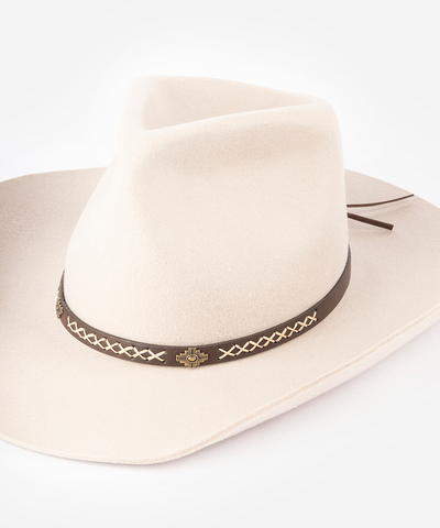 A light cream-colored felt cowboy hat with a dark brown band featuring a decorative braided pattern and a small gold-toned cross emblem, set against a plain white background #color_dark brown