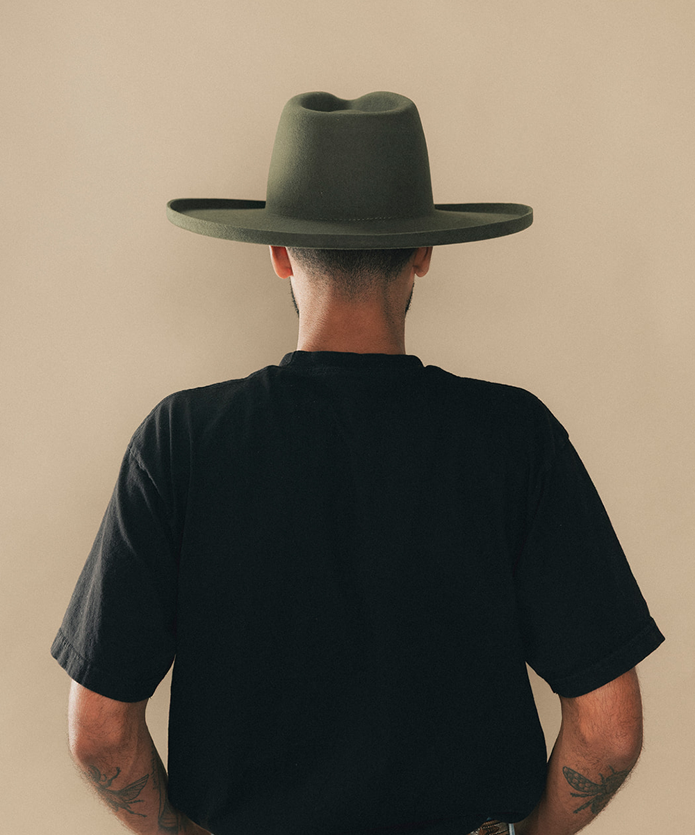 Man wearing a felt wide-brimmed hat with a beige background #color_forest green