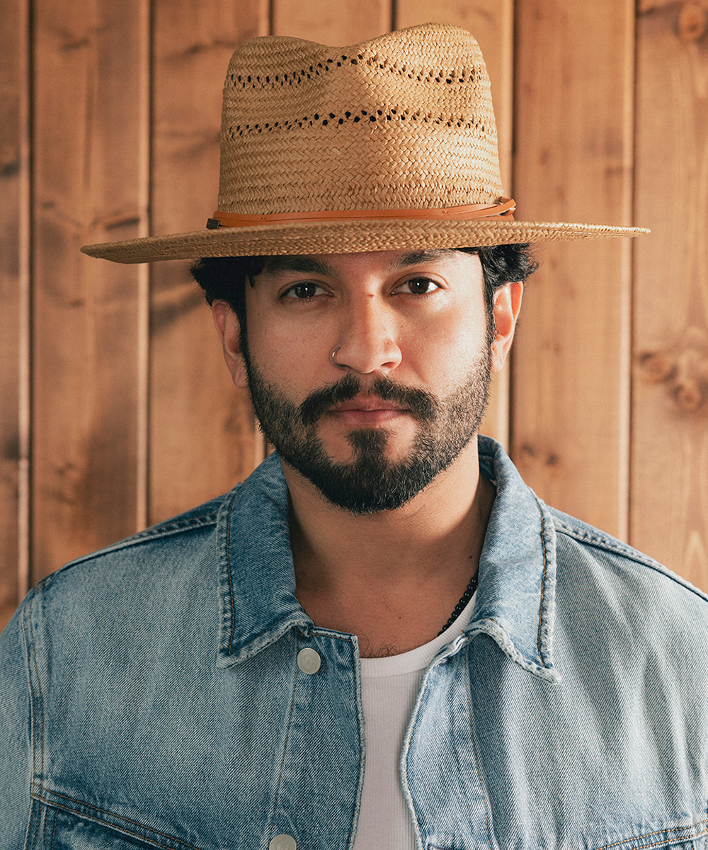 Man wearing a straw hat and denim jacket against a wooden background #color_natural