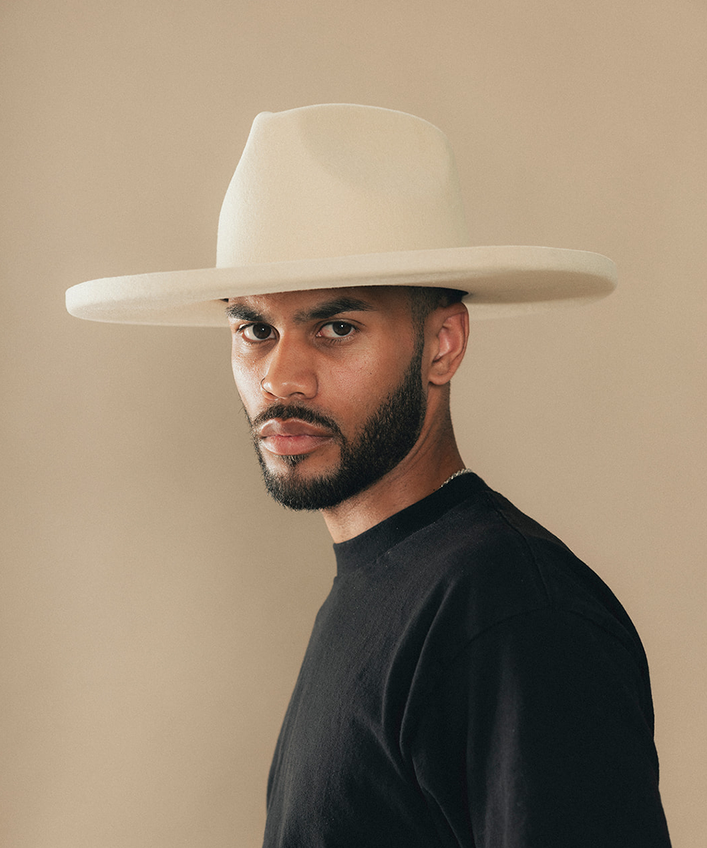 Man wearing a felt wide-brimmed hat with a beige background #color_buckskin