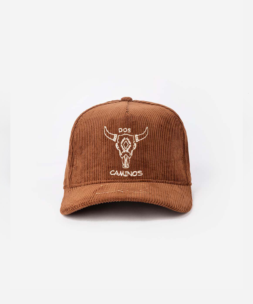 A brown corduroy baseball cap with a white embroidered bull skull graphic and the text 'DOS CAJUNOS' on the front, set against a plain white background #color_sienna