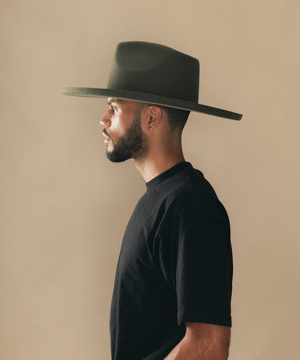 Man wearing a felt wide-brimmed hat with a beige background #color_forest green