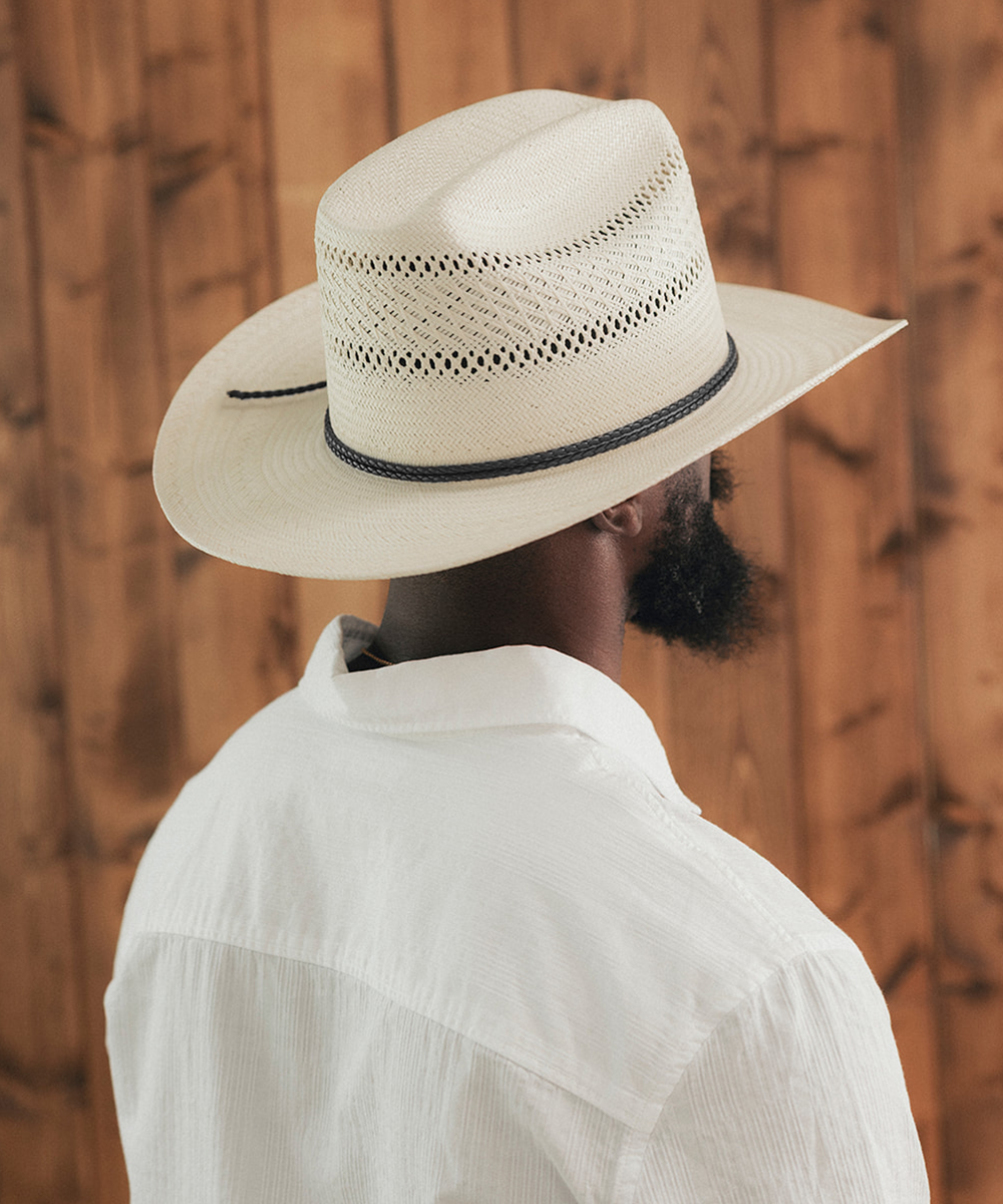 Man wearing a white cowboy hat and white shirt against a wooden background #color_ivory