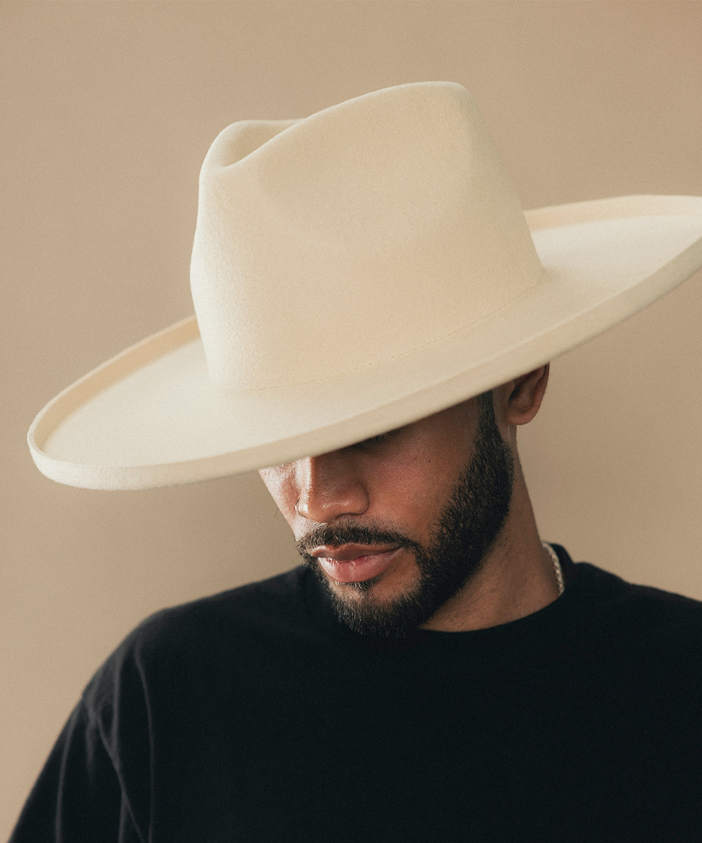Man wearing a felt wide-brimmed hat with a beige background #color_buckskin