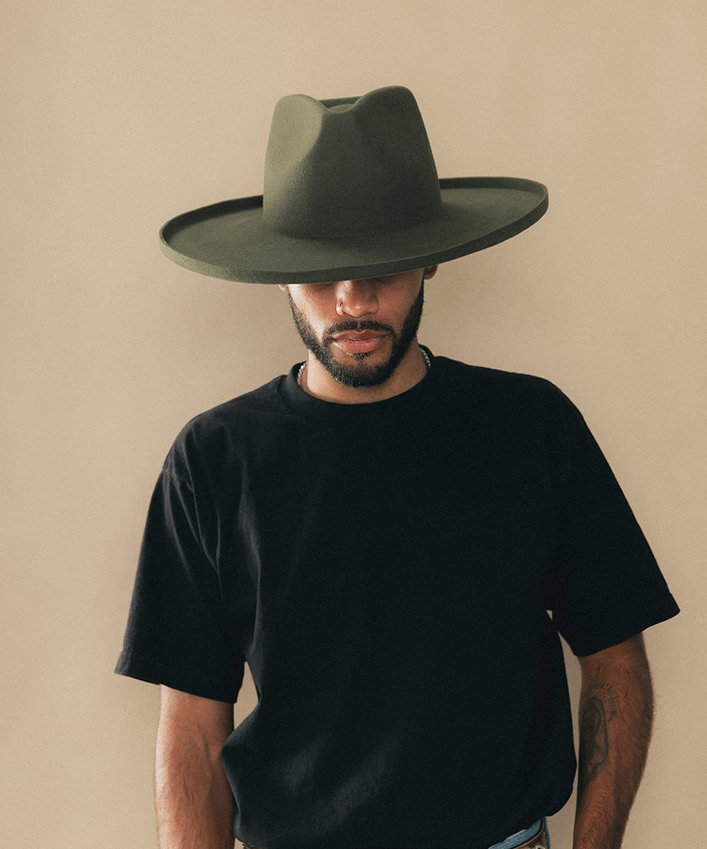 Man wearing a felt wide-brimmed hat with a beige background #color_forest green