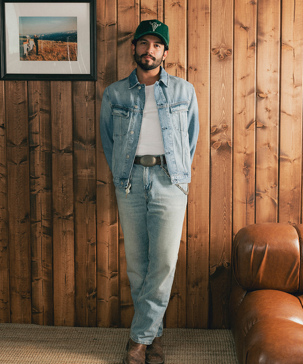 Man wearing a baseball hat and denim jacket against a wooden background #color_saguaro