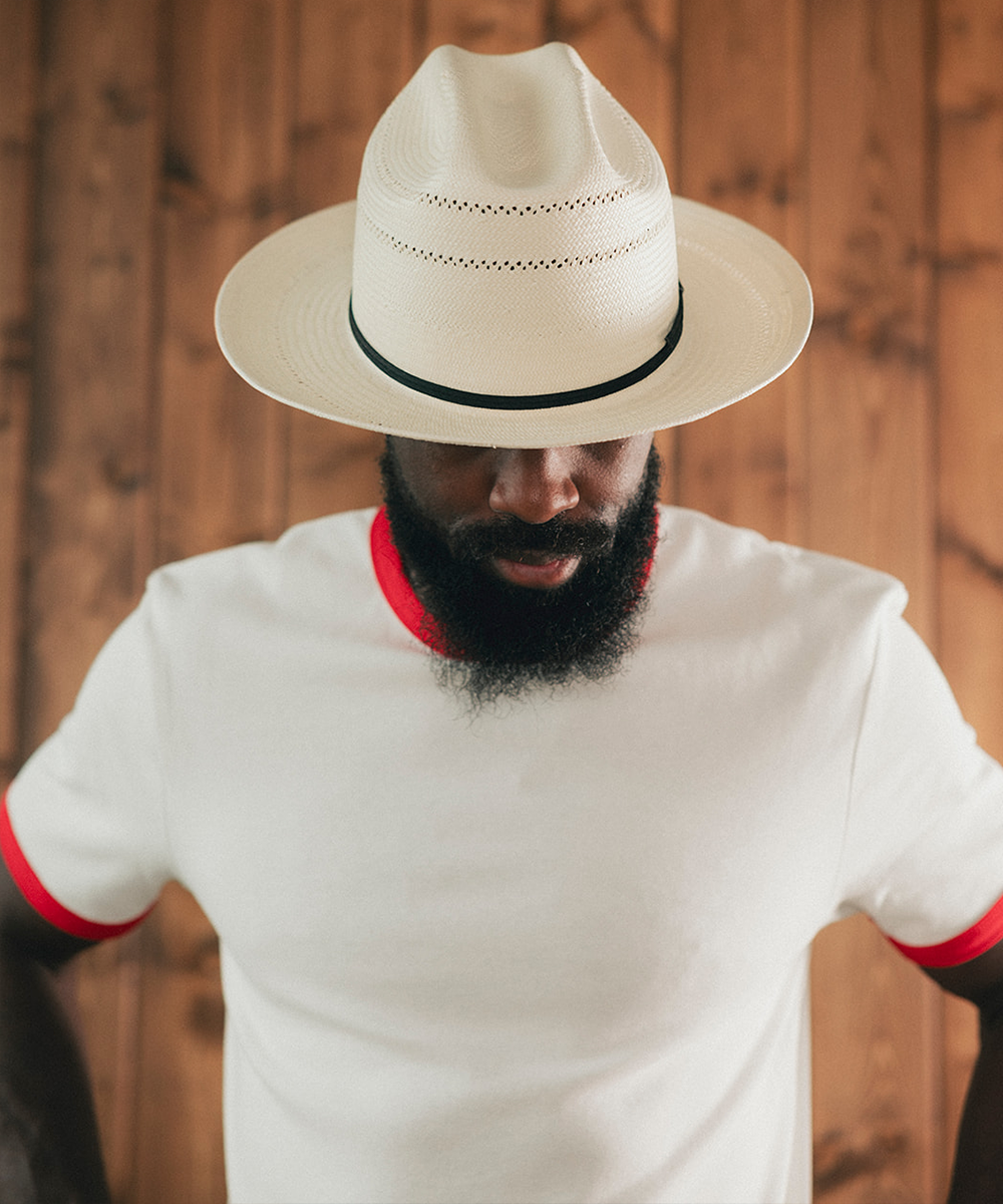 Man wearing a white Panama hat with a wooden background #color_off white