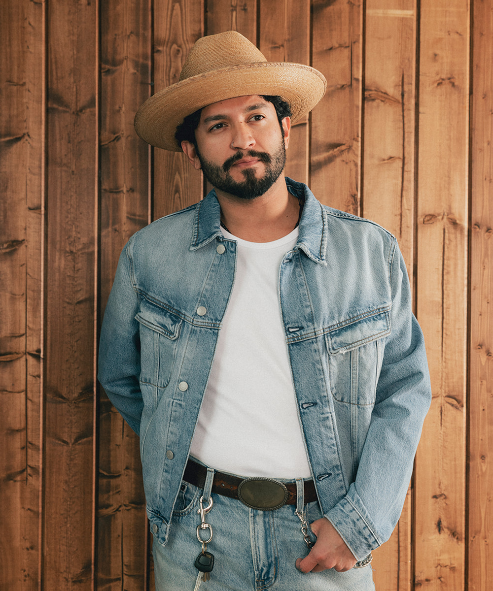 Man wearing a straw hat and denim jacket against a wooden background #color_oak