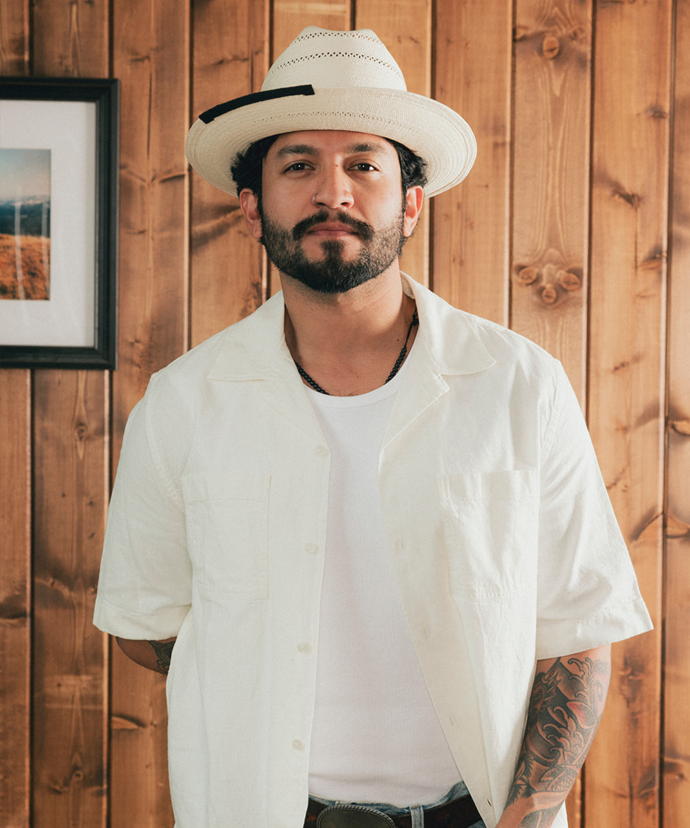 Man wearing a straw hat and white shirt against a wooden background #color_charcoal