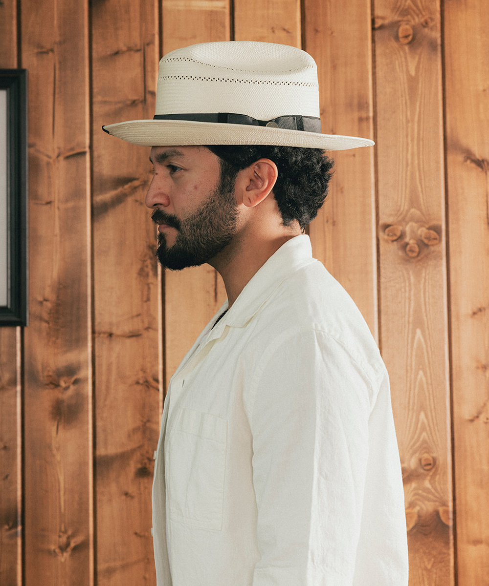 Man wearing a straw hat and white shirt against a wooden background #color_charcoal