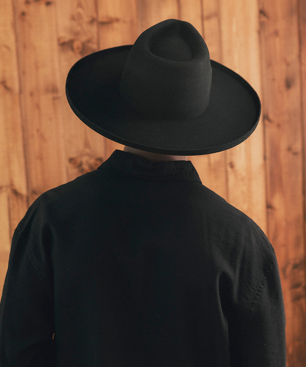 Man wearing a black hat against a wooden background #color_black