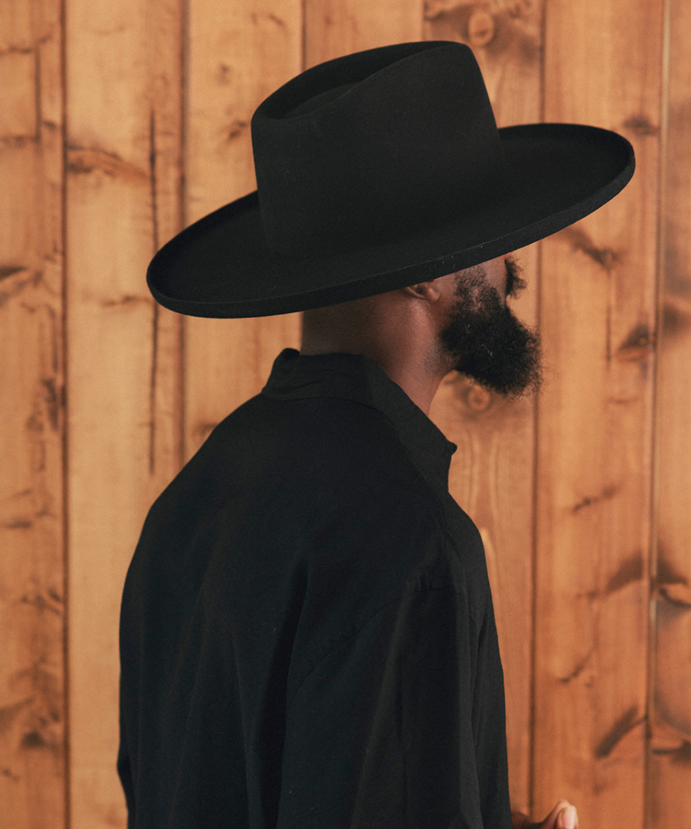Man wearing a black hat against a wooden background #color_black