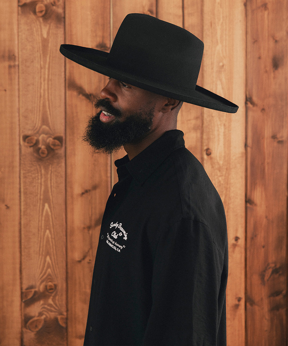 Man wearing a black hat against a wooden background #color_black