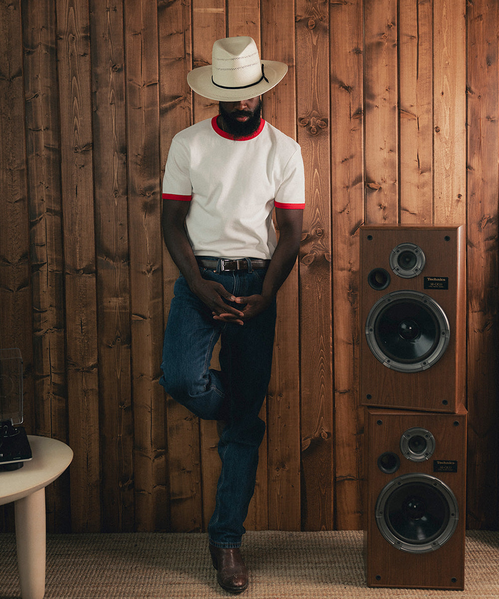 Man wearing a white straw hat and red and white shirt against a wooden background #color_ivory