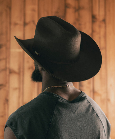 Man wearing a cowboy hat and sleeveless shirt against a wooden wall #color_hickory