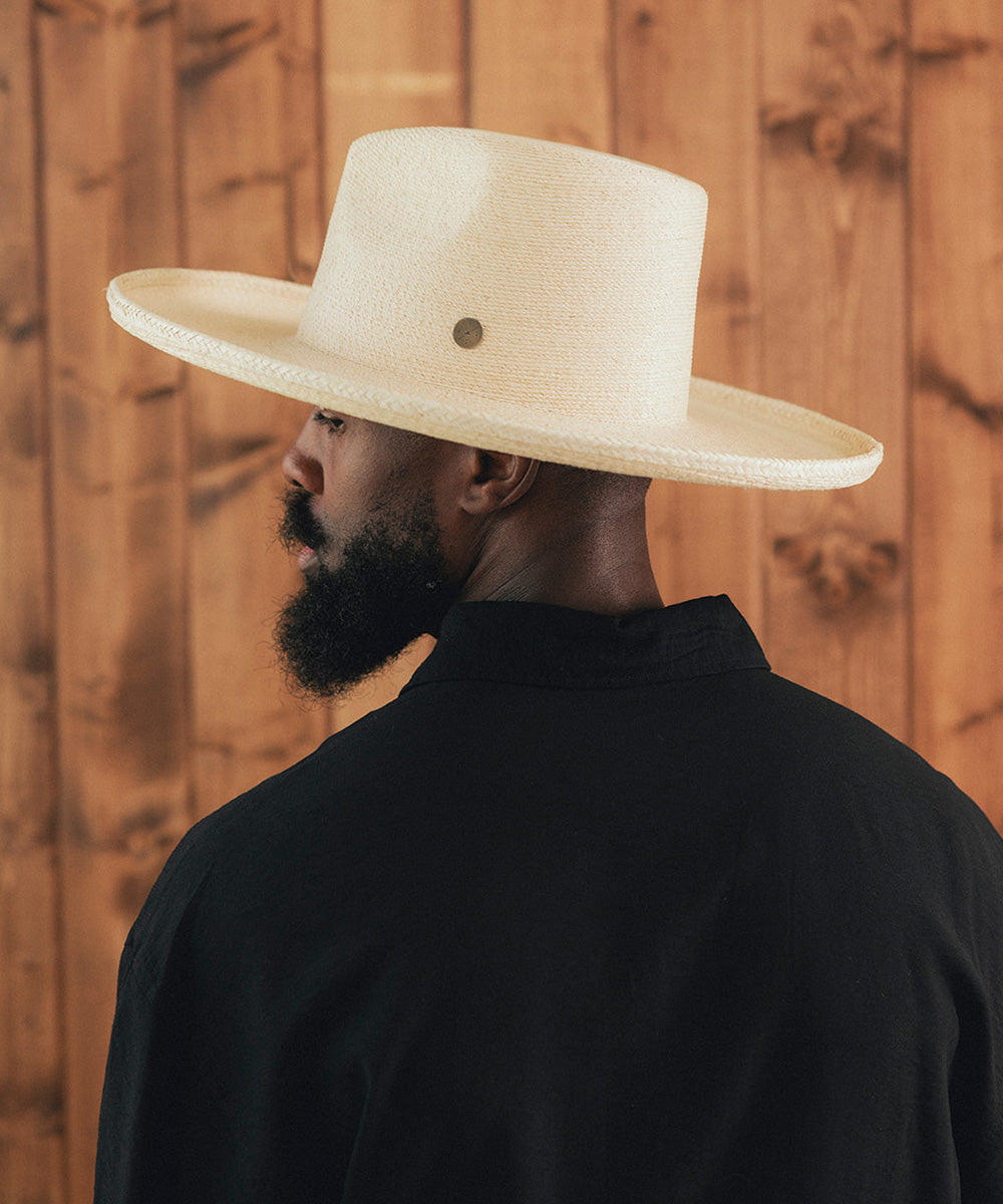 Man wearing a wide-brimmed beige hat against a wooden background #color_ivory