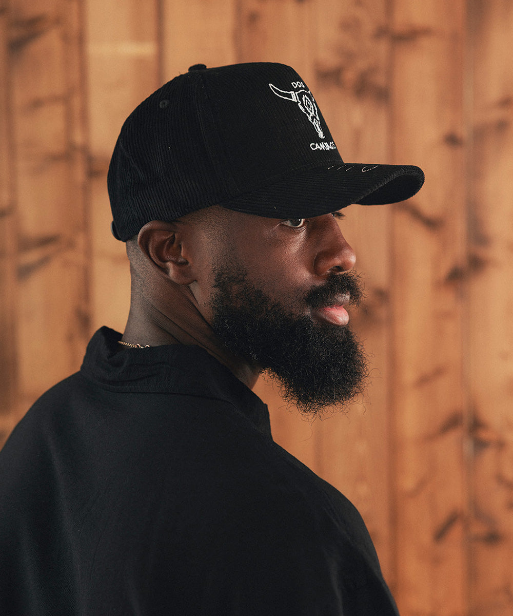 Man wearing a black cap and black shirt against a wooden wall #color_black