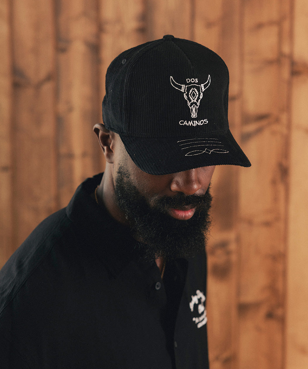 Man wearing a black cap and black shirt against a wooden wall #color_black