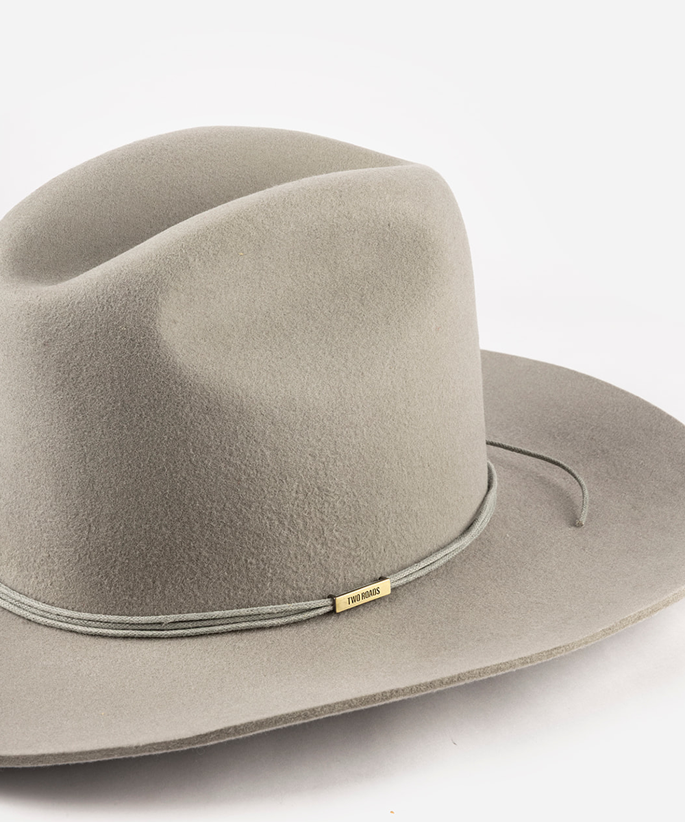 A light gray felt cowboy hat with a matching gray rope band and a small gold metal brand tag, photographed on a clean white background #color_gray