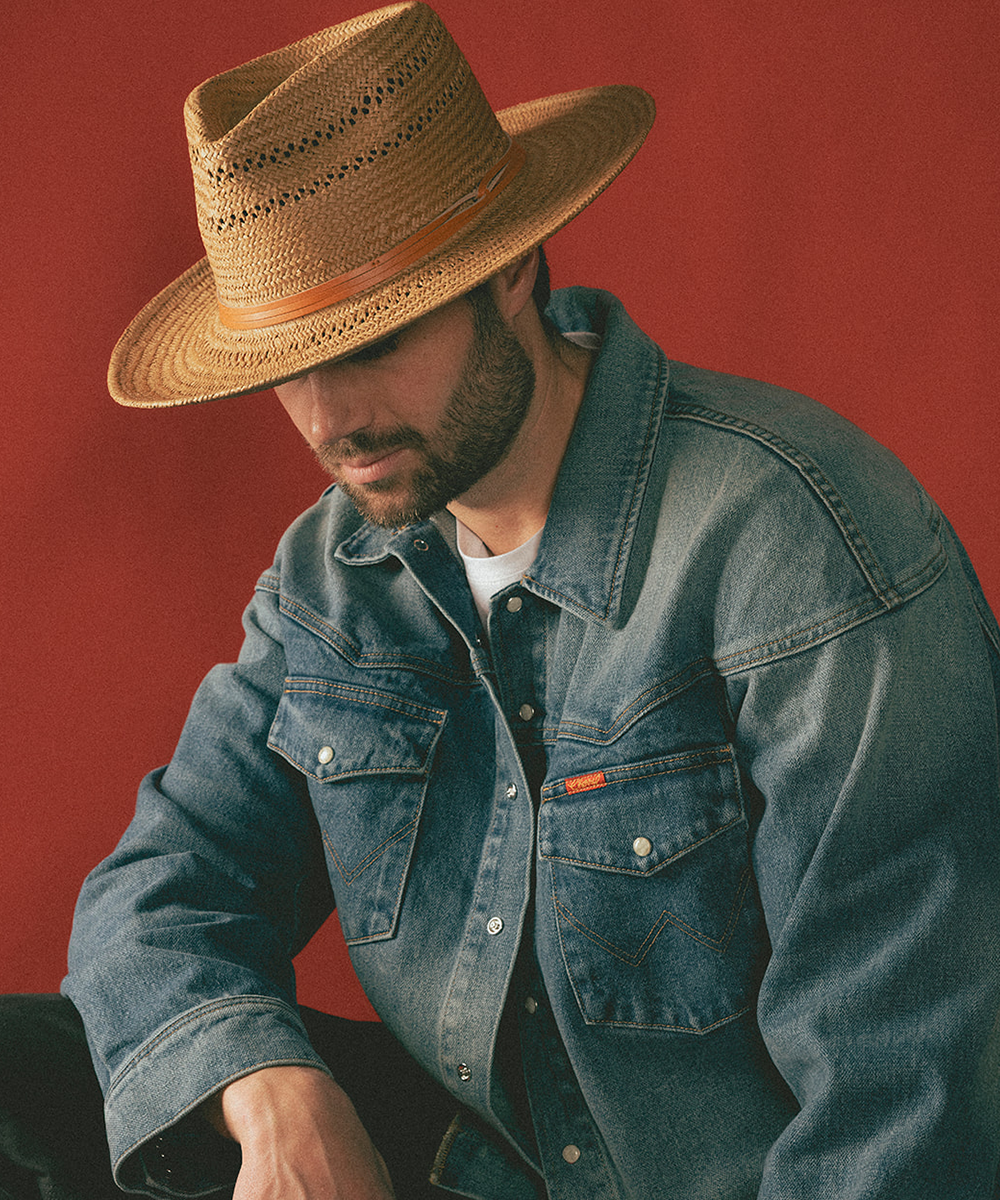 Man wearing a straw hat and denim jacket against a red background #color_natural