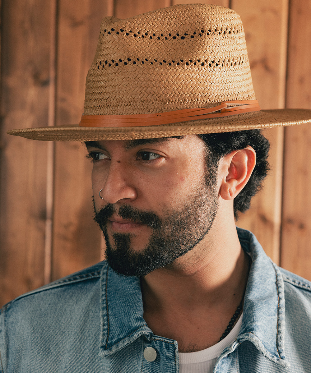 Man wearing a straw hat and denim jacket against a wooden background #color_natural