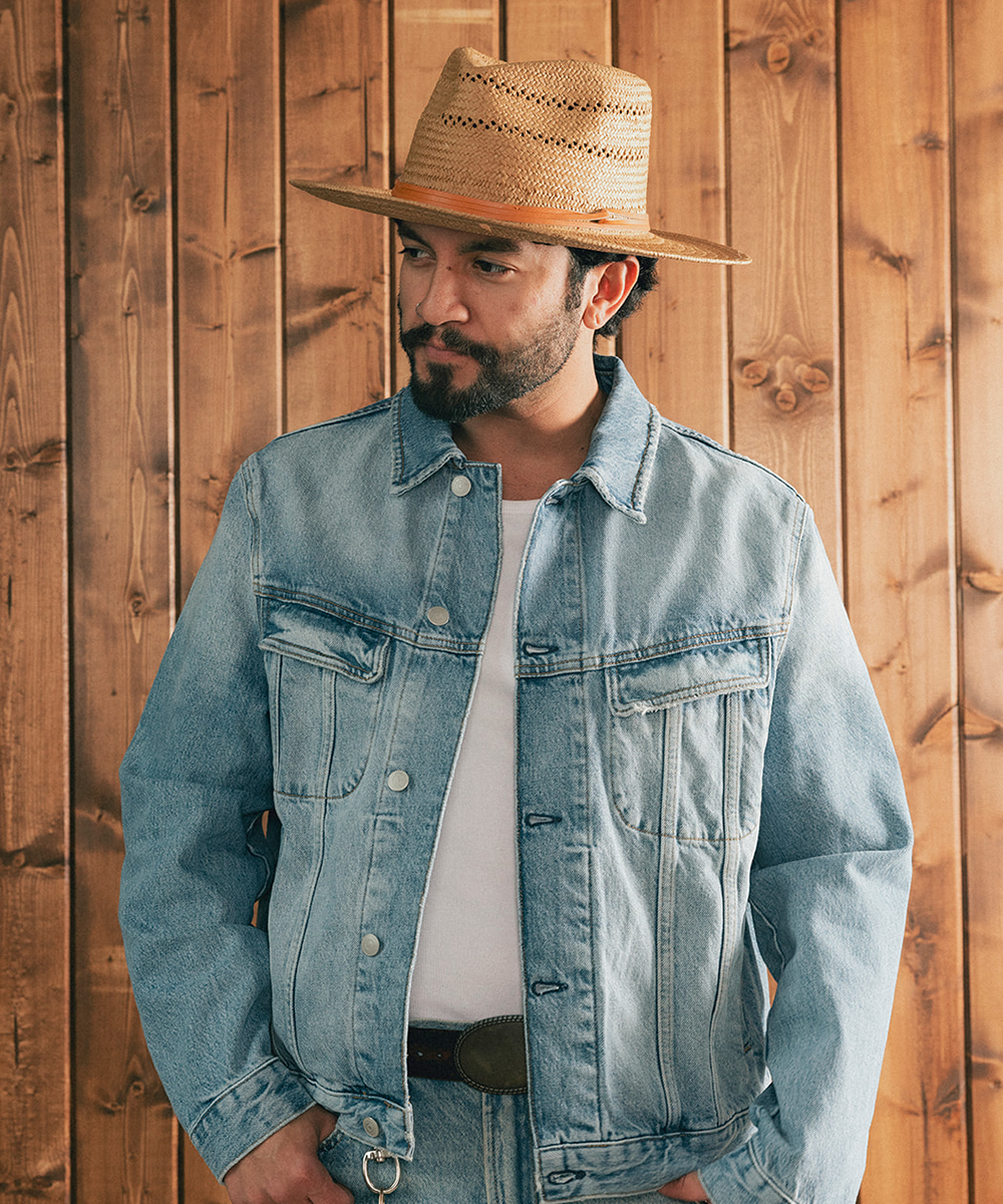 Man wearing a straw hat and denim jacket against a wooden background #color_natural