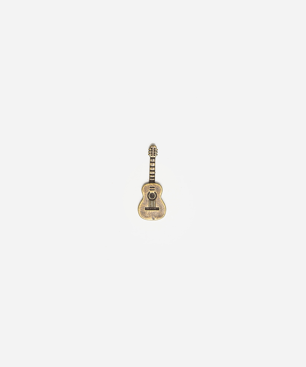 A small guitar-shaped charm or pendant with a gold-tone finish and black details, centered on a plain light gray background #color_anti gold