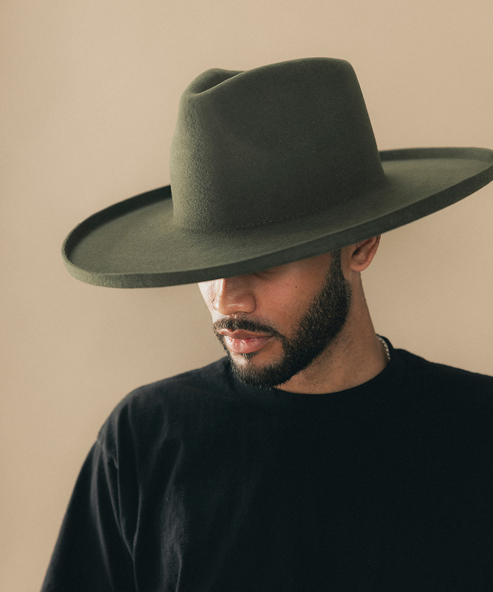 Man wearing a felt wide-brimmed hat with a beige background #color_forest green