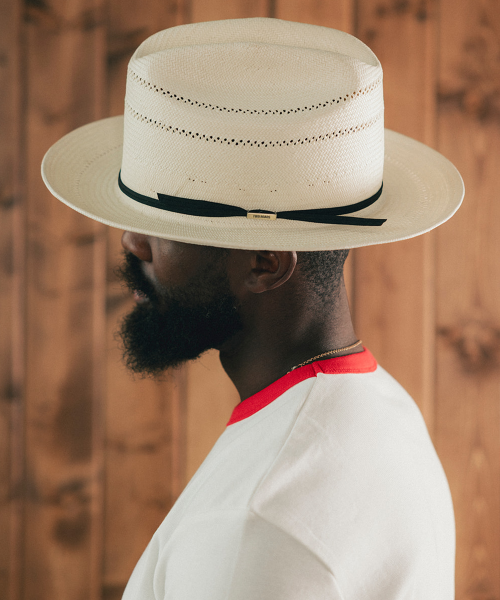Man wearing a white Panama hat with a wooden background #color_off white