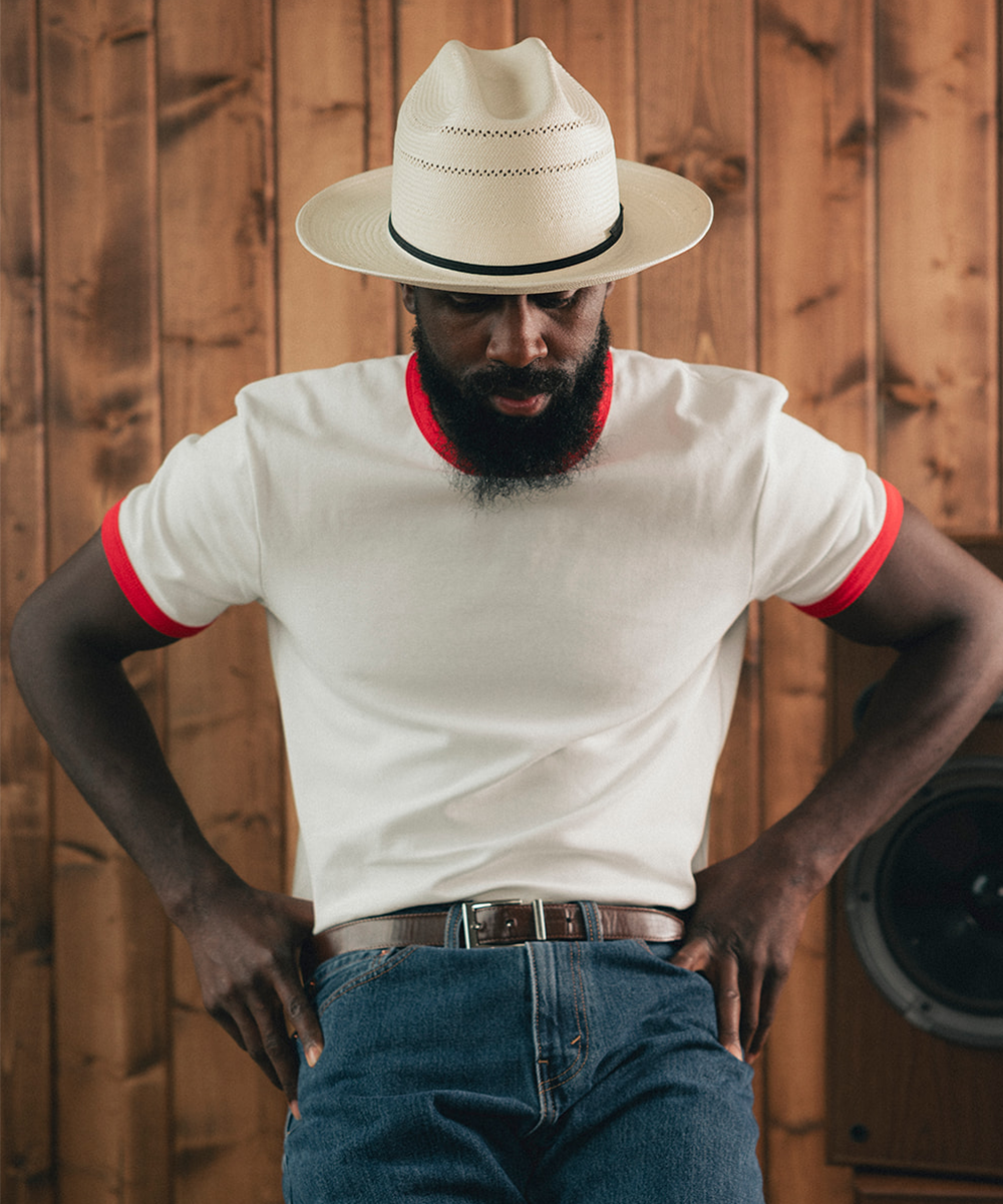 Man wearing a white Panama hat with a wooden background #color_off white