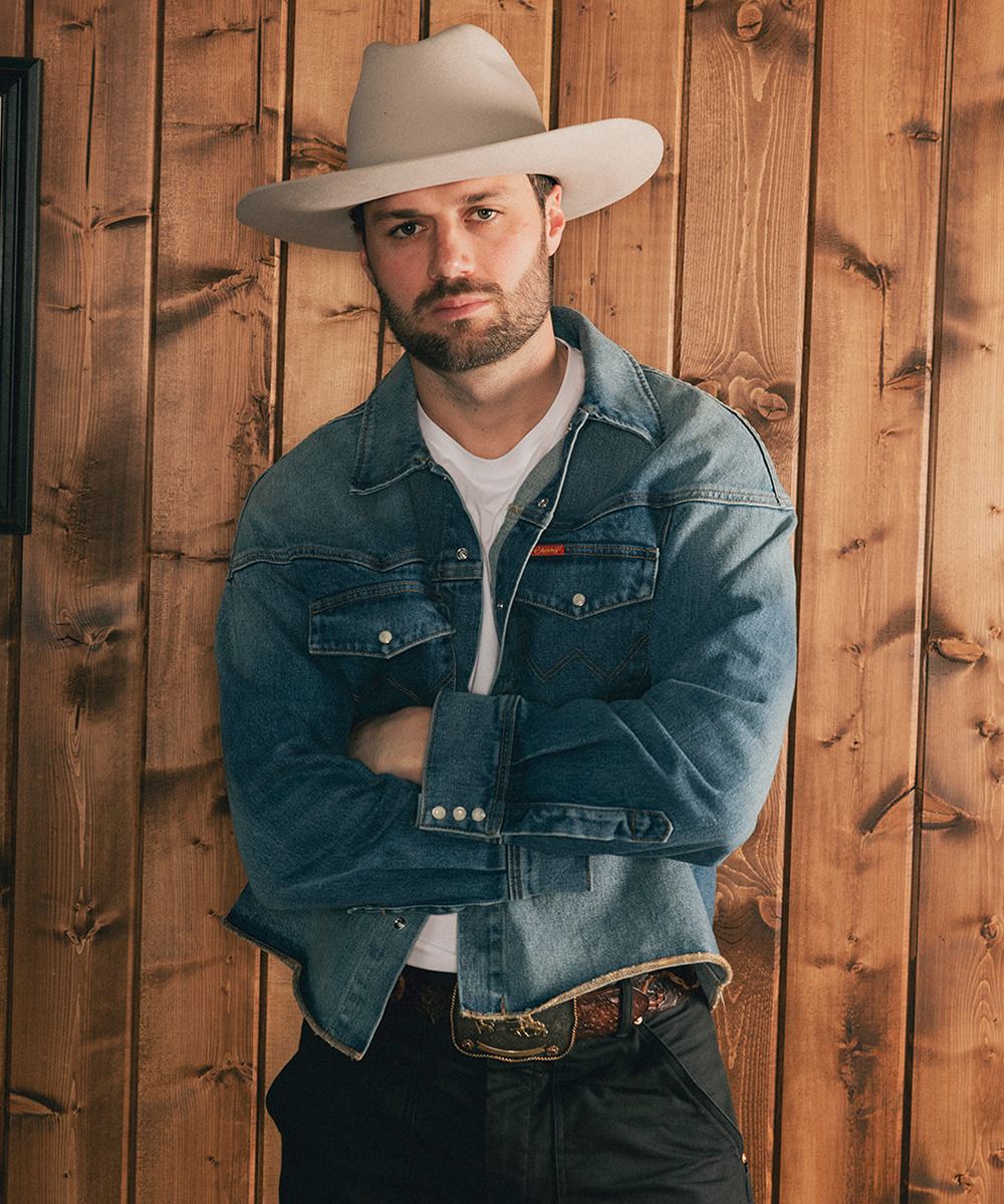 Man wearing a beige cowboy hat and denim jacket against a wooden background #color_silverbelly