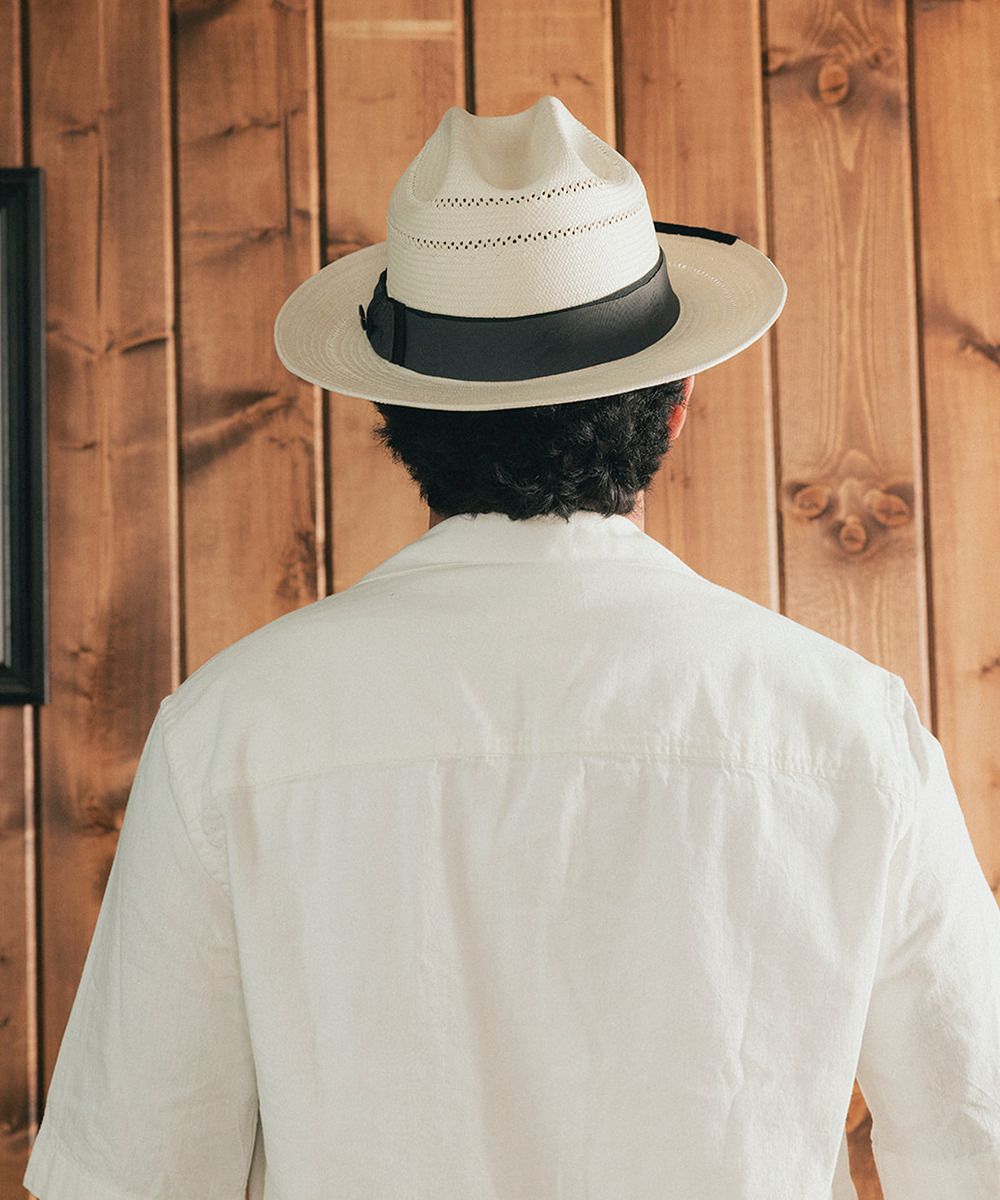 Man wearing a straw hat and white shirt against a wooden background #color_charcoal