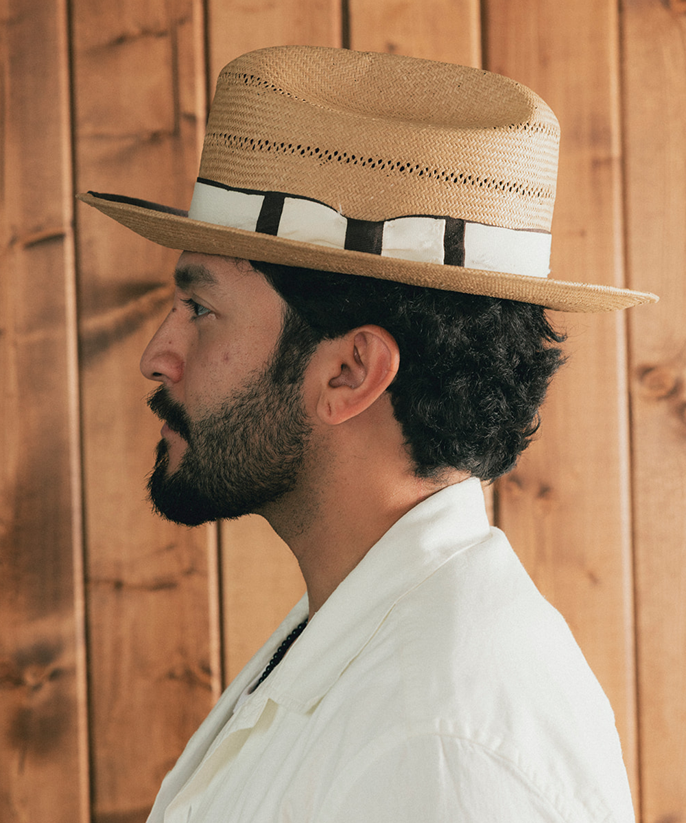 Man wearing a straw hat and white shirt against a wooden background #color_natural