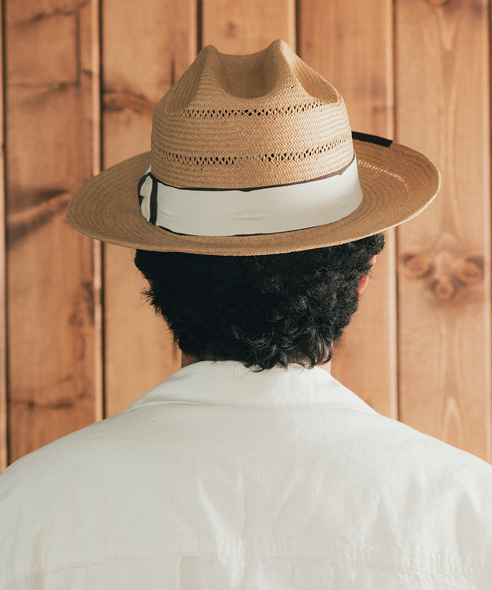 Man wearing a straw hat and white shirt against a wooden background #color_natural